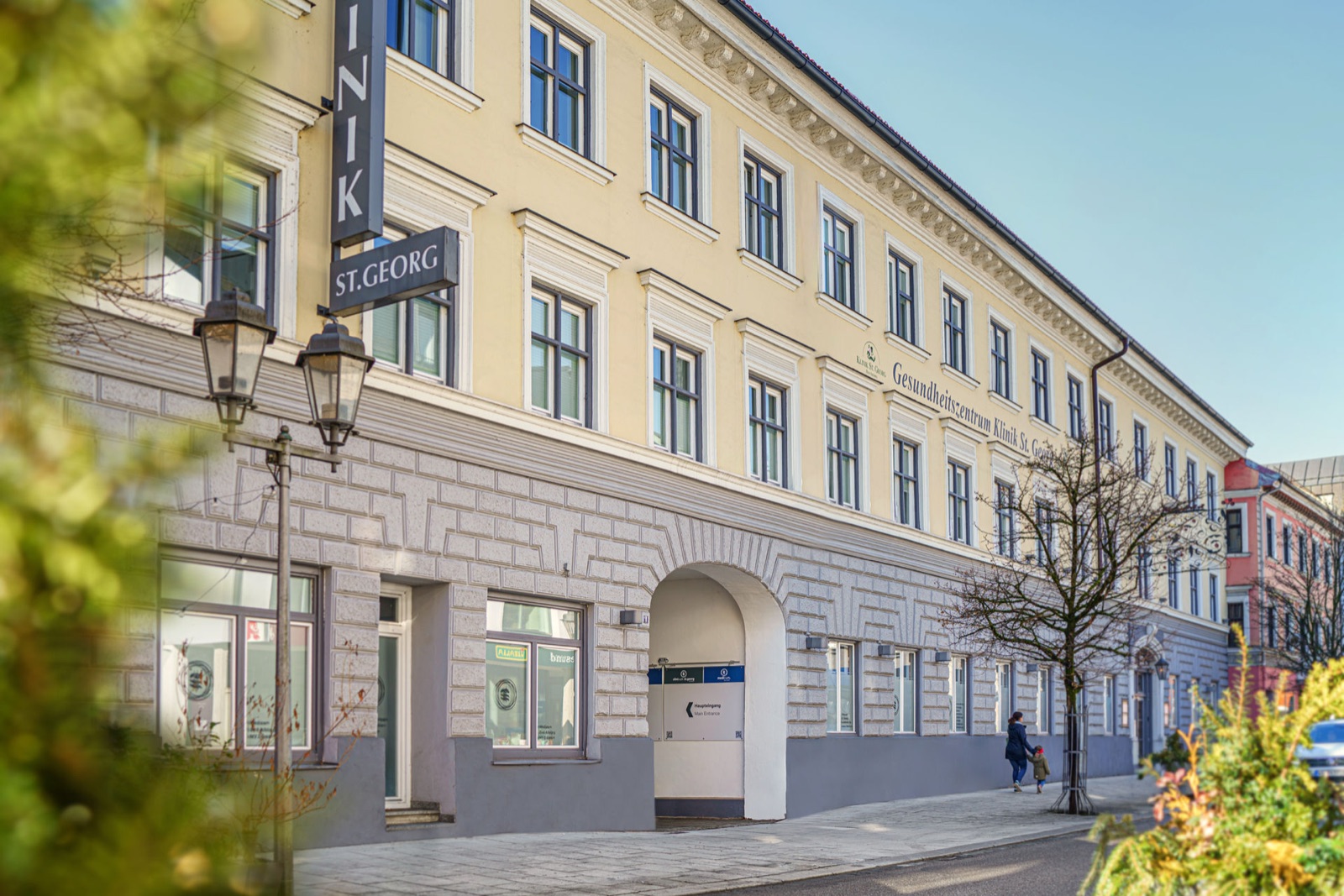 The yellow historic façade of Clinicum St. Georg in Bad Aibling with the lettering Klinik St. Georg above the entrance.